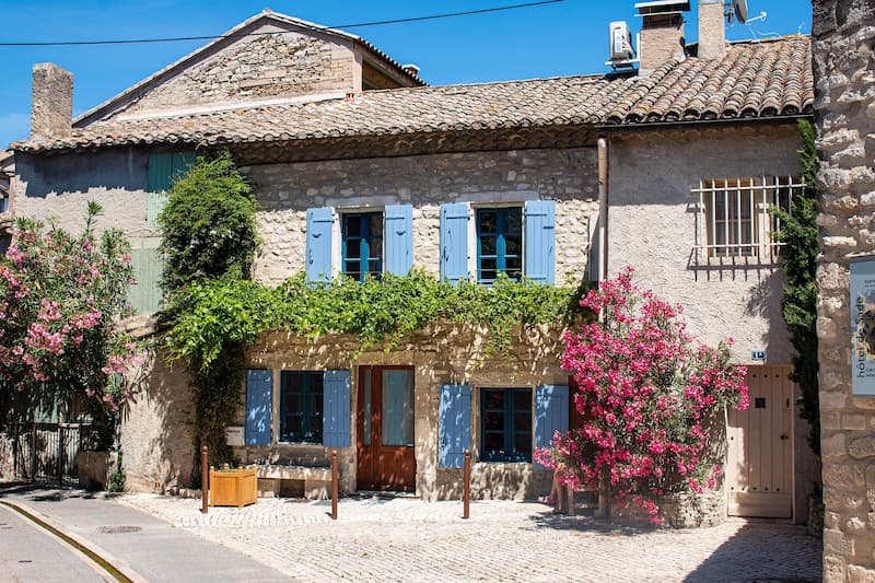 Maison en pierre avec volets bleus et bougainvilliers en Provence – chambre d’hôtes typique
